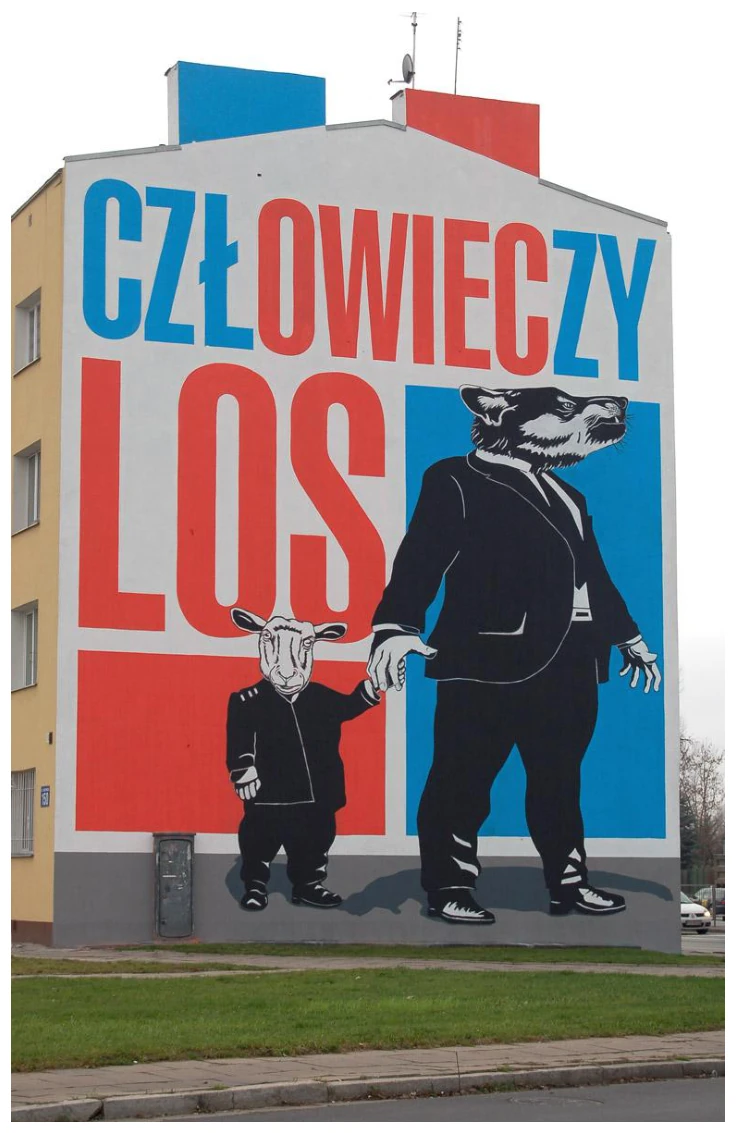 Mural „Człowieczy los” na ścianie bloku: duży napis na czerwono-niebieskim tle oraz postać wilka w garniturze trzymająca za rękę małą postać owcy w ubraniu.